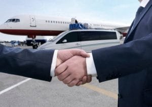 Two businessmen shake hands in front of a plane, symbolizing a successful partnership in airport limo service.