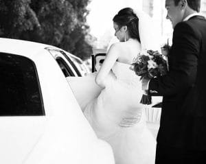 A bride and groom entering a limousine, celebrating their wedding day with a luxurious ride.