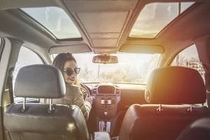 1. A woman wearing sunglasses drives a luxury car, showcasing a stylish experience from a luxury car rental service.
