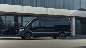 A Mercedes-Benz Sprinter van parked in front of a building, promoting van rental services.