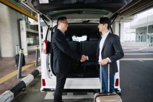 Tri State Airport Limo Two men shaking hands in front of a Tri State Airport Limo van, symbolizing a business agreement or partnership.