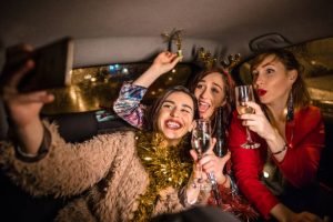 Three women enjoy a toast with champagne glasses inside a luxury limousine, celebrating a joyful moment together.
